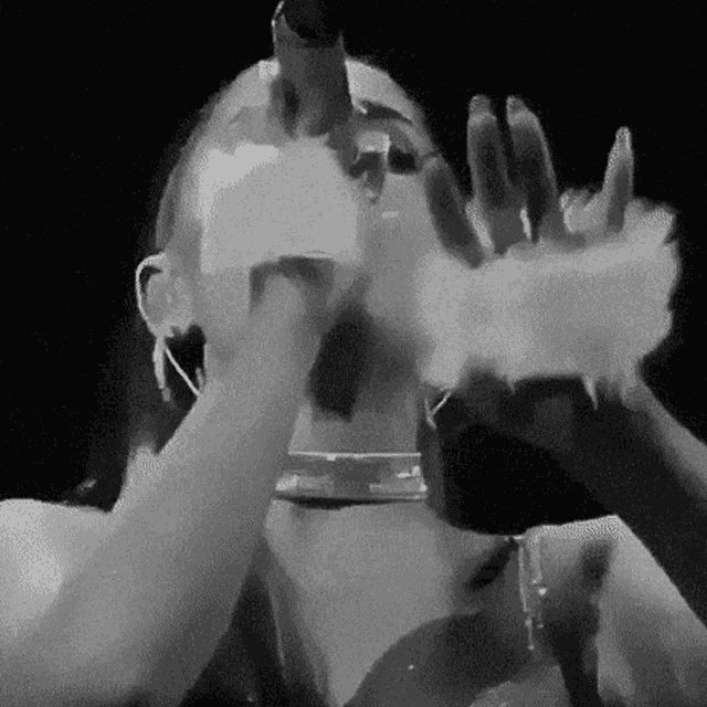 a black and white photo of a woman blowing smoke into a microphone .