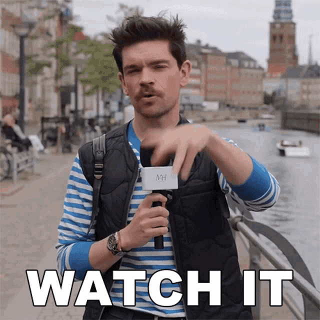 a man holding a microphone with the words watch it on the bottom