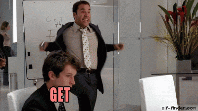 a man in a suit and tie is dancing in front of a white board that says get on it