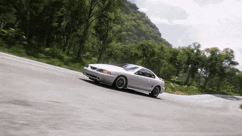 a white sports car is driving down a road with trees in the background