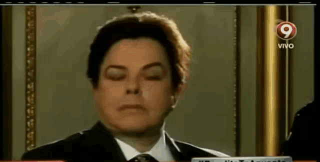 a man in a suit and tie is on a tv screen with the number 9 in the corner