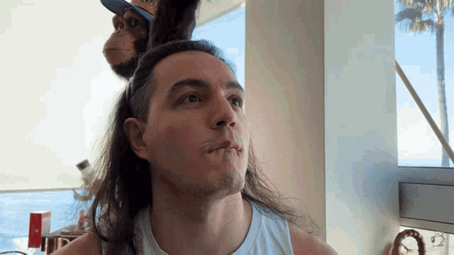 a man with long hair and a monkey on his head with a hat that says los angeles