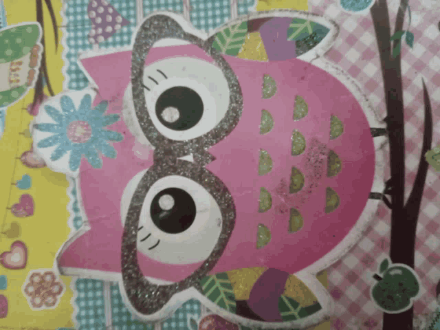 a pink owl with glasses and a flower on its face