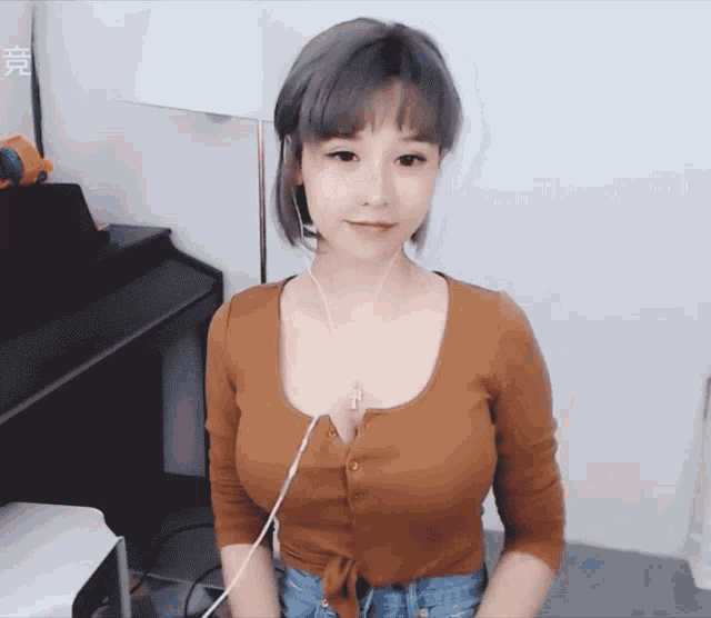 a woman wearing headphones and a brown shirt is standing in front of a white wall