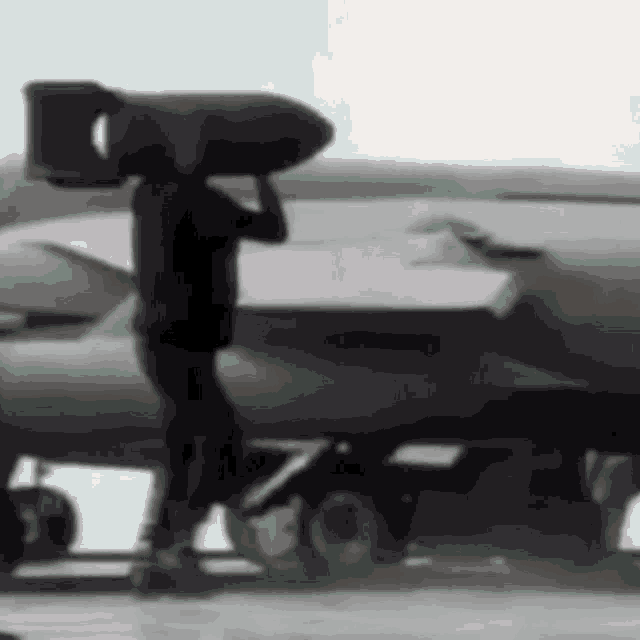 a man is carrying a large bomb on his shoulders while standing next to a plane .