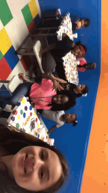 a group of young girls are sitting at a table with a colorful tablecloth