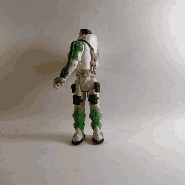 the back of a white and green action figure with a hood