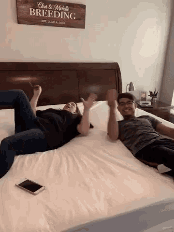 a man and a woman are laying on a bed with a sign above them that says chris & michelle breeding