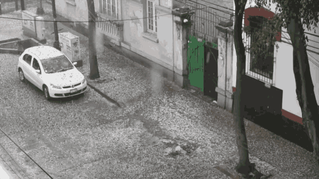 a white car is parked in front of a building that has a green gate