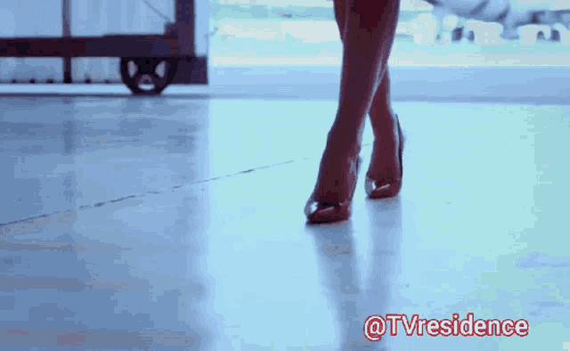 a woman wearing high heels is walking on a concrete floor with the words @tvresidence above her