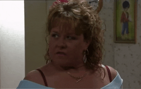 a woman wearing a bra and a necklace has a picture of a boy hanging on the wall behind her