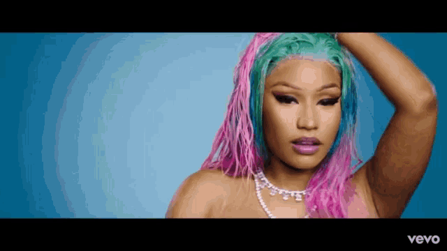 a woman with pink and green hair and a pearl necklace