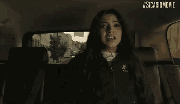 a woman is sitting in the back seat of a car with her head in her hands .
