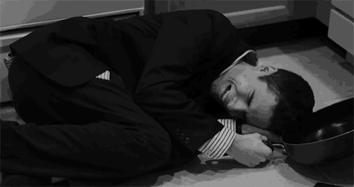 a man in a suit is laying on the floor with his head on a pot