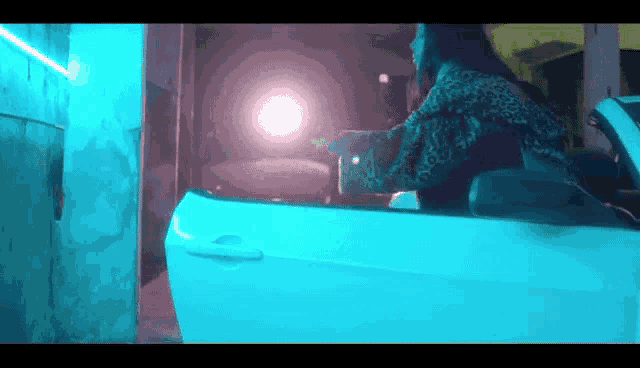 a woman is sitting in a white car with the door open in a dark room .