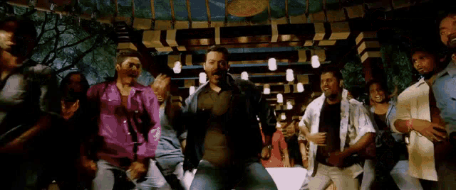a man is dancing in front of a crowd of people in a room .