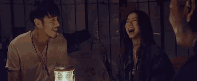 a man and a woman are laughing together while sitting next to each other in a dark room .