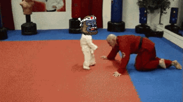 a man in a red kimono is kneeling down next to a little girl in white karate uniform