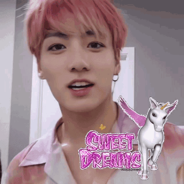 a young man with pink hair is wearing a pink shirt with a picture of a unicorn and the words sweet dreams on it .