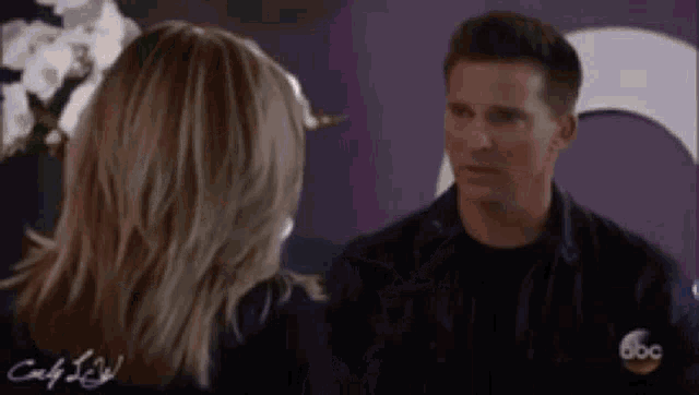 a man and a woman are standing next to each other and talking to each other .