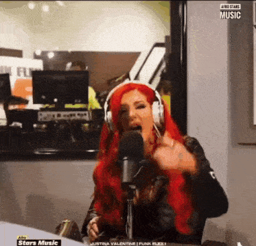 a woman with red hair is wearing headphones and singing into a microphone