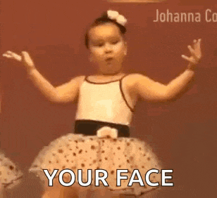 a little girl in a tutu is dancing with her arms outstretched and says `` your face '' .