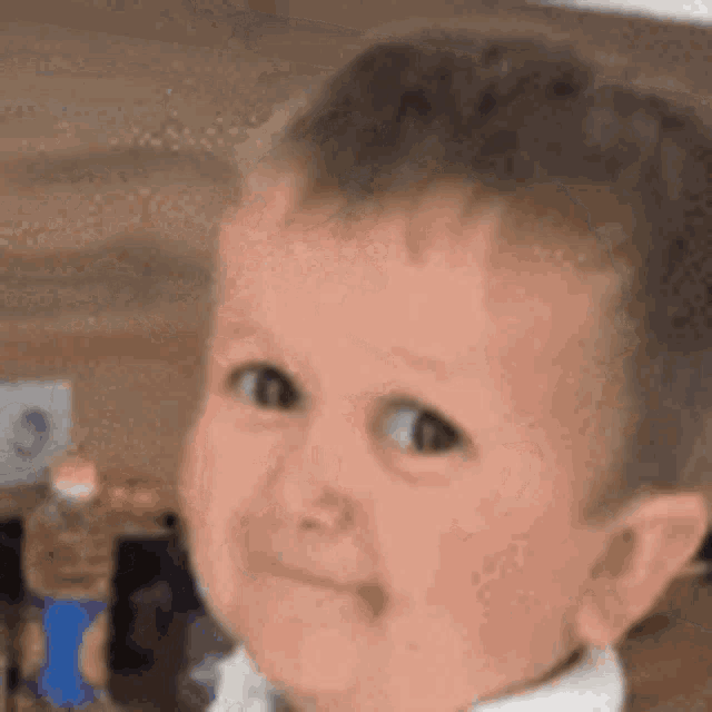 a close up of a baby making a funny face with his hand on his face .