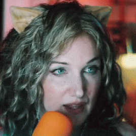 a woman with cat ears on her head holds a carrot in her mouth