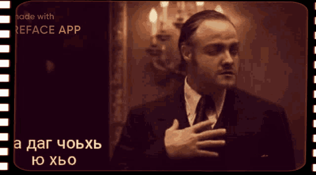 a man in a suit and tie has his hand on his chest in front of a screen that says reface app