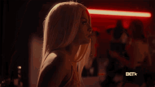 a woman is in a dark room with a bet logo behind her