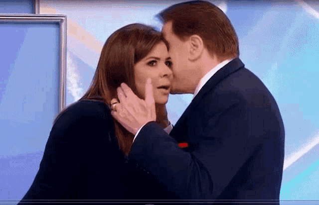 a man kisses a woman on the cheek while she looks surprised