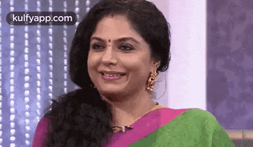 a woman wearing a pink and green saree is smiling .