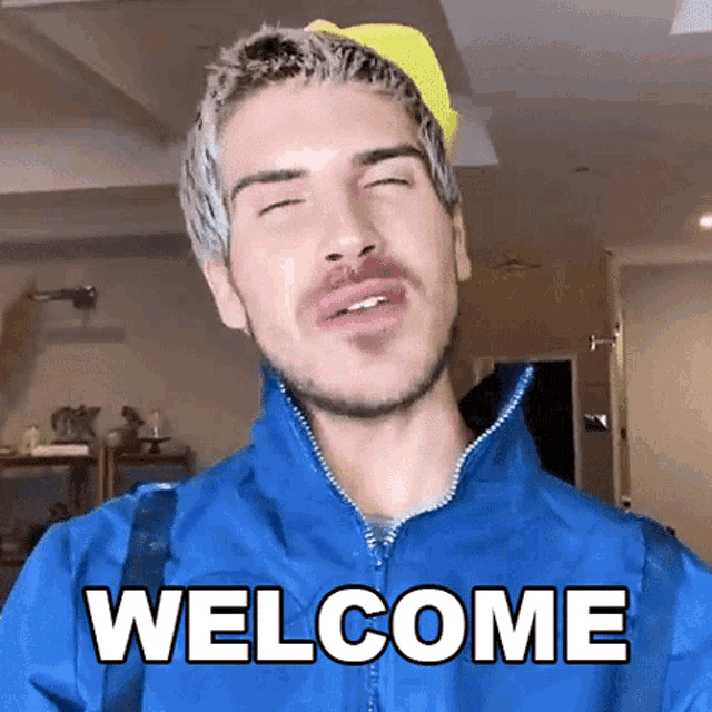 a man wearing a blue jacket and a yellow hat is saying welcome .