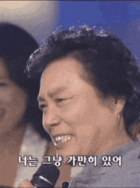 a woman is smiling while holding a microphone with korean writing on the bottom