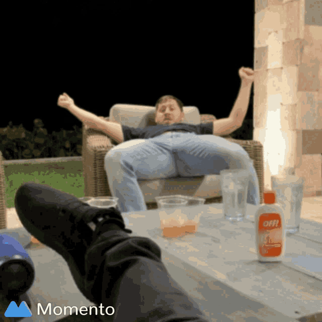 a man sits in a chair with his legs crossed and a bottle of off on the table