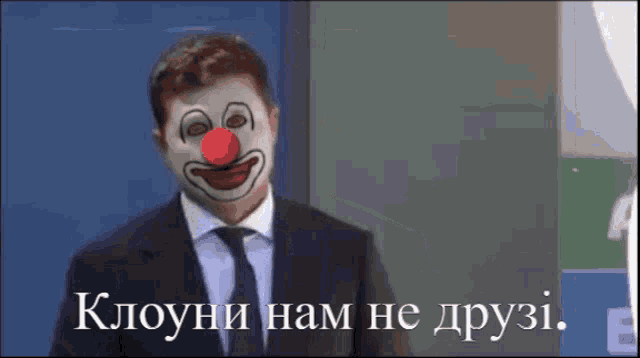 a man in a suit has a clown mask on his face