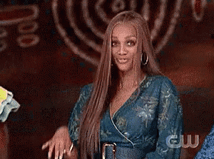a woman with long hair is waving her hand in front of a cw logo