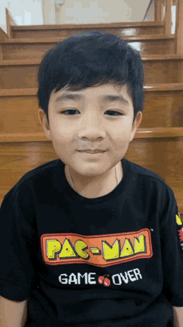 a young boy wearing a pac man game over t-shirt