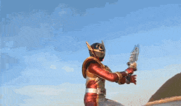 a man in a superhero costume is holding a sword in his hand .