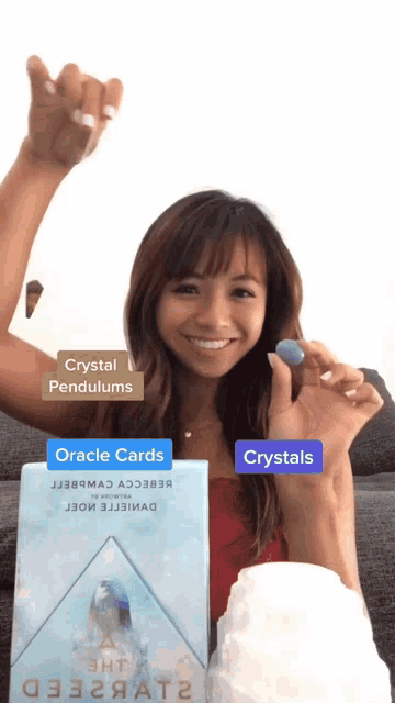 a woman holding a crystal next to a box that says crystal pendulums