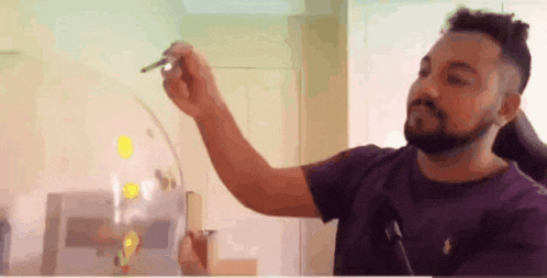 a man in a purple shirt is holding a pen in his hand and drawing on a white board .