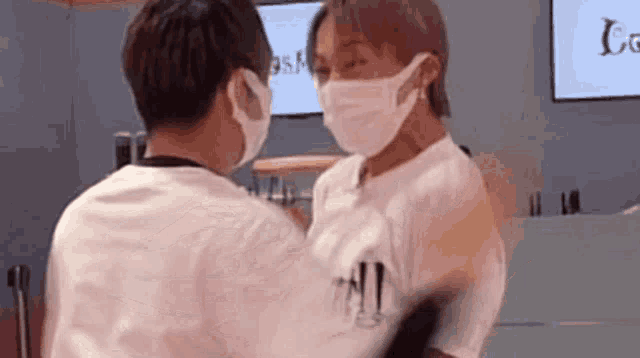 two men wearing face masks are standing next to each other .