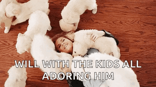 a woman is laying on the floor with a bunch of white puppies surrounding her .