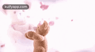 a teddy bear is standing in front of a pink background with petals flying around it .