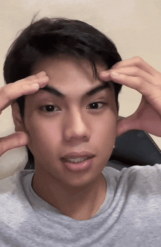 a close up of a man 's face with his hands on his head
