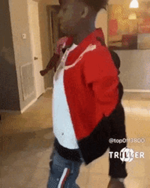a young boy in a red jacket is standing in a room