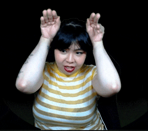a woman in a yellow and white striped shirt has her hands up