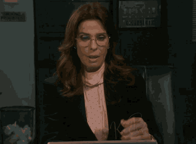 a woman wearing glasses and a pink polka dot blouse has a kb logo on her wrist