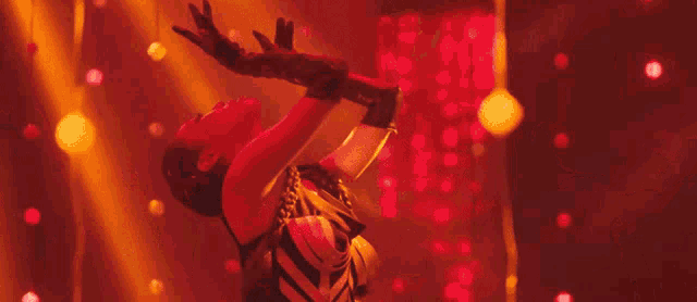 a woman is dancing in a dark room with red lights .