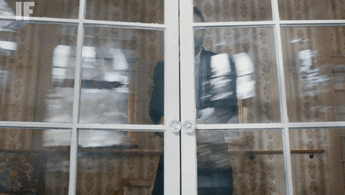 a blurred image of a person behind a glass door with the letters if visible